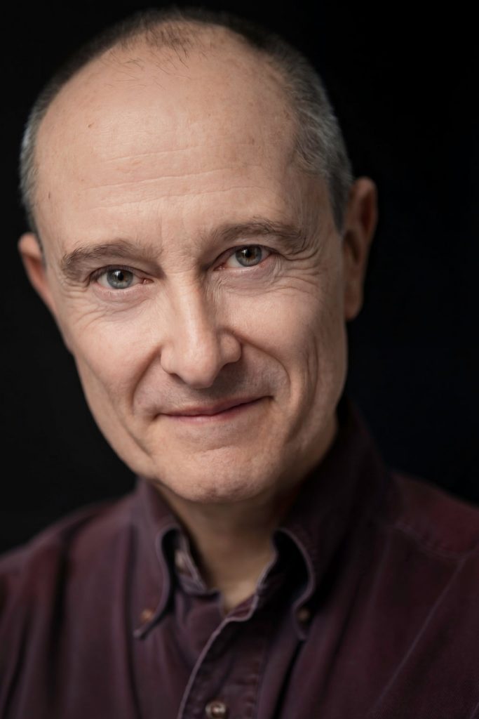 Andrew Sellon Legit Headshot Serious Expression and Slight Smile on Black Background. Photo: Will O’Hare Photography