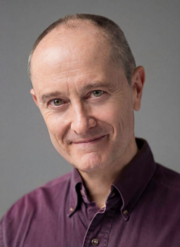 Andrew Sellon Legit Headshot Warm Smile with Light Gray Background. Photo: Will O’Hare Photography